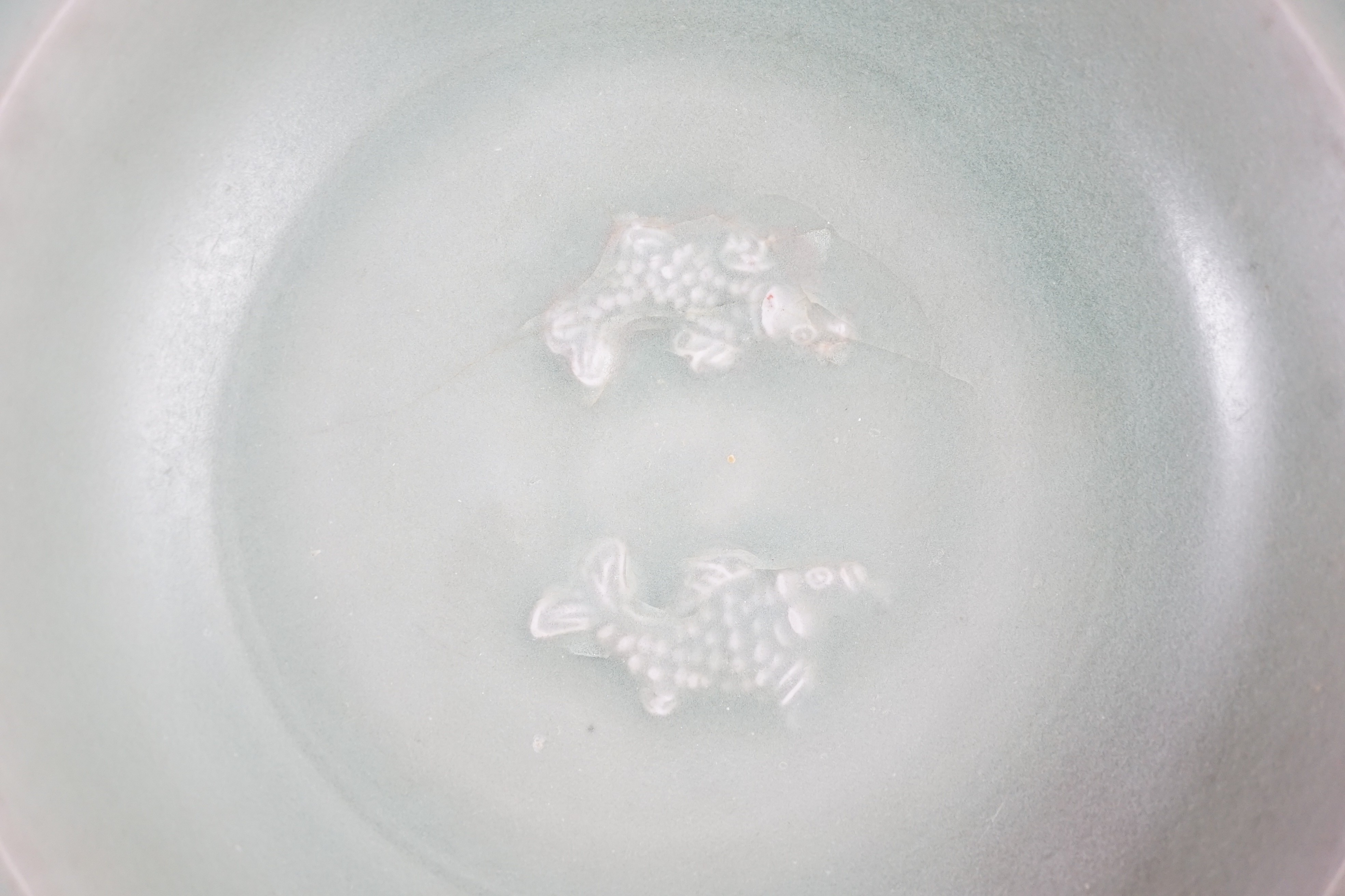 A Chinese Longquan celadon ‘twin fish’ marriage dish, Southern Song - Yuan dynasty, 13th/14th century, 22cm diameter, cracks to base